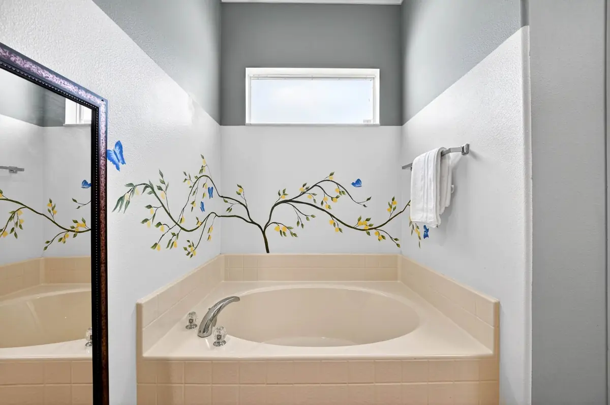 Garden tub with a hand-painted tree and butterflies on the wall