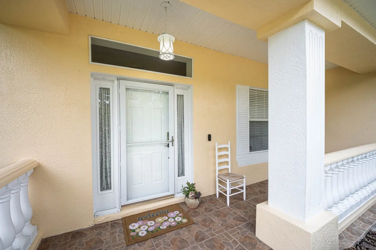 Covered front entry with white columns and a welcome mat